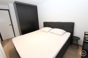 een slaapkamer met een groot wit bed met een zwart hoofdeinde bij Appartement spacieux à Knokke in Knokke-Heist