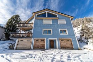 a blue house with two garage doors in the snow at Chesa Chavriol - Samedan in Samedan