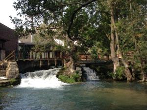 un pont sur une rivière avec une cascade dans l'établissement Logis - Hôtel & Restaurant Moulin Des Forges, à Saint-Omer-en-Chaussée