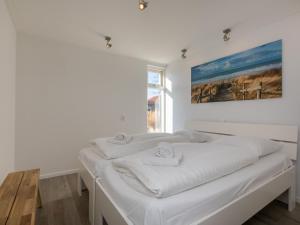 a white bedroom with a bed with towels on it at Holiday Home in Zeeland Family-Friendly in Serooskerke