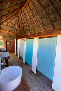 La salle de bains est pourvue d'une baignoire blanche et d'un plafond en bois. dans l'établissement Balam Camping & cabañas, à Holbox