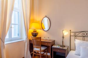 a bedroom with a bed and a desk and a mirror at Archontiko Eleni Hotel in Andros