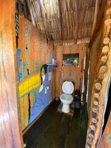 a bathroom with a toilet with a painting on the wall at Balam Camping & cabañas in Holbox Island