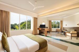 1 dormitorio con cama y escritorio y 1 habitación con sofá cama en Sangam Hotel, Thanjavur, en Thanjāvūr