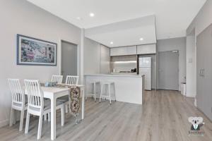 a kitchen and dining room with a table and chairs at KOZYGURU Penrith Cosy 2BED 2BATH APT + FREE Parking NPE081 in Penrith