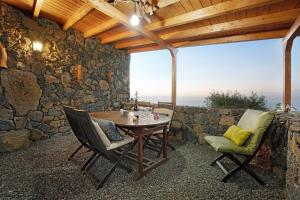 a patio with a table and chairs and a stone wall at El Nogal in San Juan de la Rambla