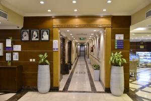 un pasillo en un edificio con dos plantas grandes en Al Jury Residence Hotel Suites, en Al Khobar