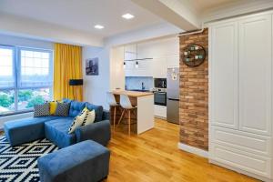 a living room with a blue couch and a kitchen at Scandinavian Apartment in Rădăuţi