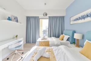 a blue and white bedroom with two beds and a desk at Luxury JBR · Marina View · 5* Beach Resorts Access in Dubai