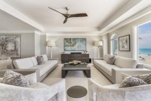 a living room with white furniture and a ceiling fan at Luxurious Condo with Private Ocean Views Directly on Seven Mile Beach condo in Dog City