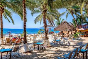 a beach with chairs and palm trees and the ocean at PB4 Nitta in Nuevo Vallarta