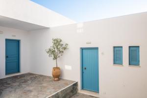 una habitación con puertas azules y una planta en un jarrón en Kritikakis Village Hotel en Ios Chora