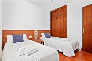 een slaapkamer met 2 bedden met witte lakens en blauwe kussens bij Villa etxe txekia in Cala Galdana