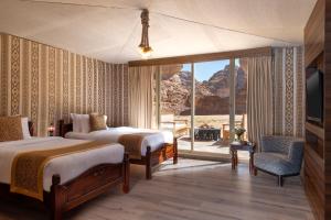 um quarto de hotel com duas camas e uma grande janela em Shaden Resort em Al-ʿUla