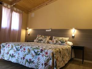 1 dormitorio con 1 cama con colcha de flores en Hostal La Posada de Mari, en La Cabrera