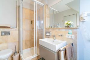 La salle de bains est pourvue d'un lavabo et d'une douche. dans l'établissement Apartment Hotel Schreier, à Lindau
