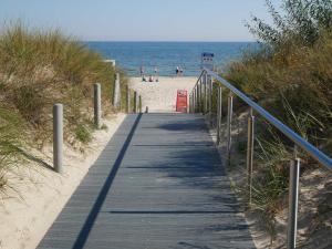 einen Holzsteg zum Strand mit Leuten auf dem Sand in der Unterkunft Villa Vineta in Bansin