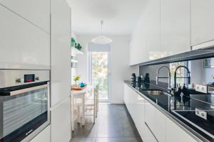 a kitchen with white cabinets and black appliances at Santo Amaro Beach Apartment in Oeiras