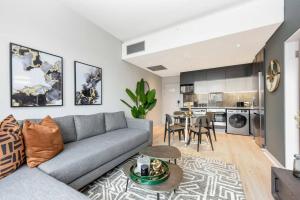 a living room with a gray couch and a kitchen at Stylish Apartment in a 5 star hotel in Johannesburg