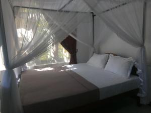 a bedroom with a bed and a window with curtains at Sisila Villa in Bentota