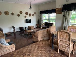 a living room with wicker chairs and a table at Reed Mat Lodge, Furnished Stand-alone 4 bedroomed house in Lusaka