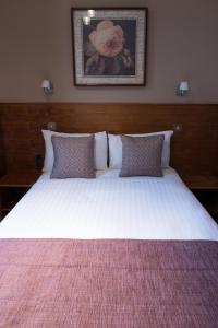 un grande letto bianco con cuscini in una camera da letto di Garden View Hotel a Londra