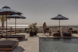 - une piscine avec des chaises et des parasols à côté de l'océan dans l'établissement Casa Cook Mykonos - Adults Only, à Ornos