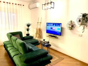 a living room with a green couch and a tv at Luxury Apartments in City Center in Durrës