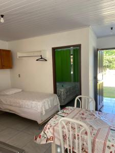1 dormitorio con 2 camas, mesa y sillas en Pousada da Heloisa, en Imbituba