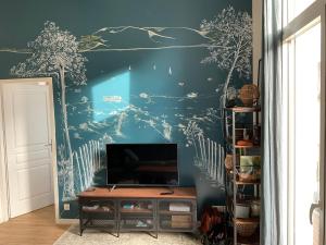 a living room with a tv and a blue wall at T2 stylé/calme et confortable in Arcachon