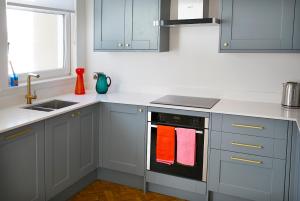 a kitchen with white cabinets and an oven with colorful towels at THE STOOP, Stunning sea views! in Scarborough