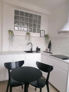 a kitchen with two black chairs and a sink at Appartement Fernand Namur in Namur