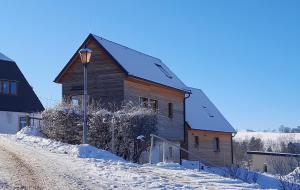 une maison en bois dans la neige avec un feu de rue dans l'établissement Ferienhäuser Seiffen, à Seiffen