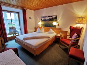 um quarto de hotel com uma cama e uma cadeira em Menkenhof em Reit im Winkl