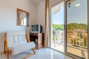 Una sala de estar con una silla y un televisor y una ventana. en Apartments Katica's Place, en Prizba