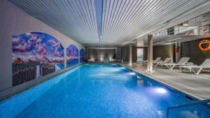 a large swimming pool with blue water in a building at Roc Blanc Hotel & Spa in Andorra la Vella