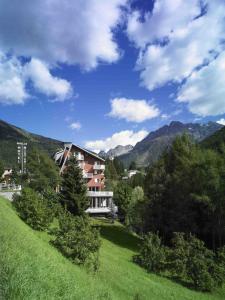 a building on a hill with mountains in the background at Hotel Mirella in Ponte di Legno
