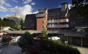 a large building with a mountain in the background at Hotel Mirella in Ponte di Legno