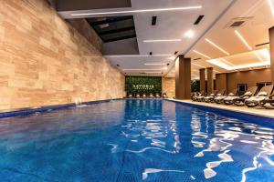 ein großer Pool in einem Hotel mit Stühlen in der Unterkunft Astoria Luxury & SPA in Gnjilane