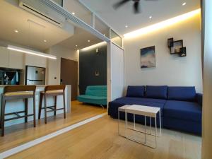 Una sala de estar con un sofá azul y una cocina. en Star Suite 5min Walk to KLCC Netflix, en Kuala Lumpur