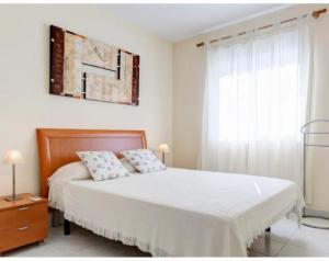 a bedroom with a large bed with white sheets and a window at Los Jasminez in Denia