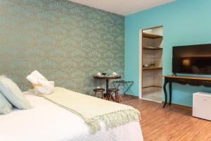 a bedroom with a bed and a television and a table at Pousada Jardon in Campos do Jordão