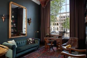 a living room with a couch and a desk and a mirror at Pulitzer Amsterdam in Amsterdam