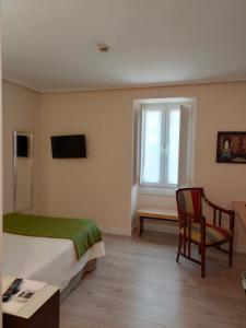 a bedroom with a bed and a chair and a window at Hotel Arrope in Haro