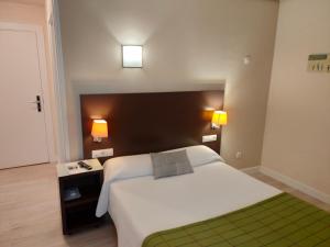 Hotel Arrope في هارو: غرفة نوم بسرير ابيض كبير ومصباحين