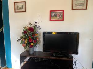 un televisor en una mesa con un jarrón de flores en Gite en Normandie, en Rugles
