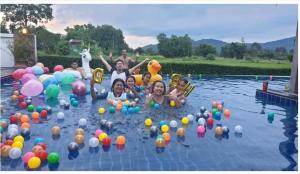 un grupo de personas en una piscina con globos en Mountain View Pool Villa en Nakhon Nayok