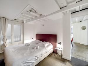 a white bedroom with a large white bed and windows at Confortable appartement pour 4 pers à Paris by Weekome in Paris
