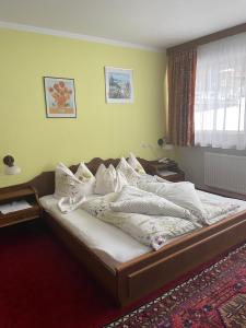 a bedroom with a bed with white sheets and pillows at Gästehaus Eberl - Rita in Finkenberg