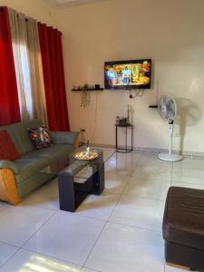 a living room with a couch and a tv at Maison Oceane a Zac MBAO in Kammba